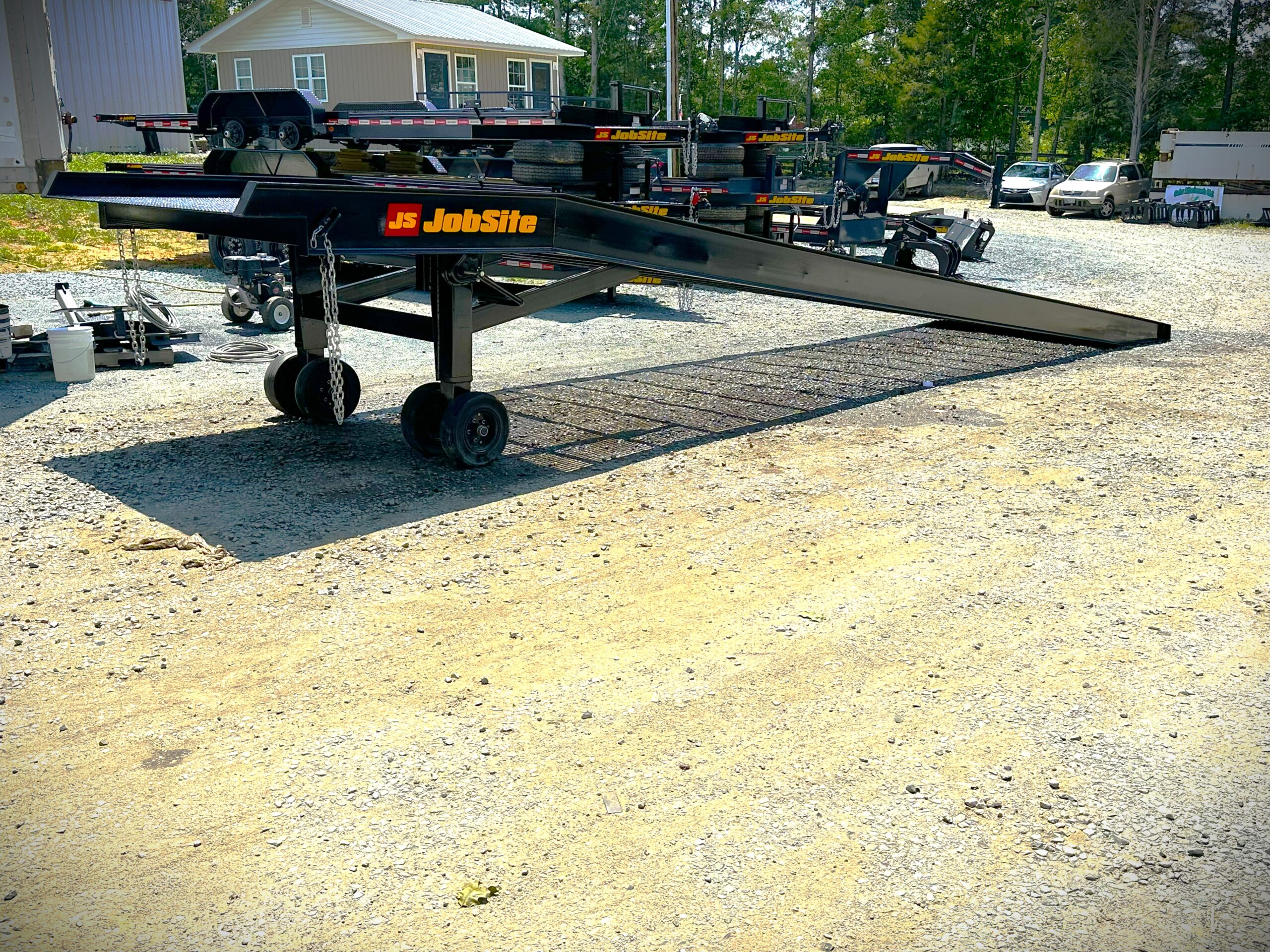 Heavy duty mobile yard ramp with offroad wheels and adjustable legs. Trailers behind ramp all featuring the Jobsite logo